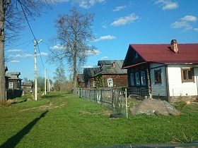 просторная улица с зеленой травой между рядами деревянных домов старой российской деревни