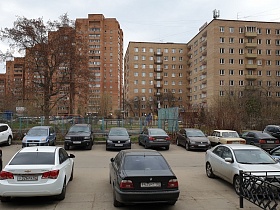 припаркованные машины на асфальтированой площадке у резного кованного забоа перед зданием столовой СССР