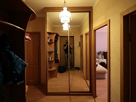 шкаф-купе с зеркальными дверцами на высоту прихожей в углу у входной двери в гостиную простой квартиры молодоженов на втором этаже высотки