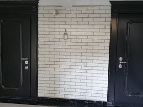 черные современные входные двери в квартиры из светлого коридора подъезда жилого кирпичного дома