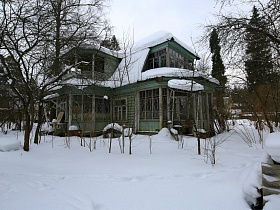 шапки снега на крыше двухэтажной деревянной советской дачи художника с овальной террасой на зимнем участке