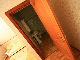 открытая дверь в ванную комнату с ванной, раковиной и шкафчиком, санузлом на втором этаже съемного дома в сосновом лесу
