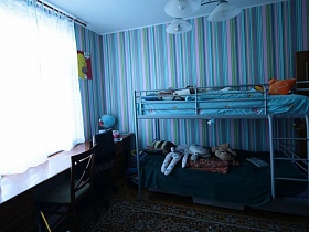 двухярусная детская кровать с лестницей и мягкими игрушками у стены с полосатыми обоями в детской комнате семейной трешки