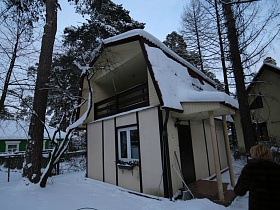 небольшой двухэтажный домик с крыльцом на дачном участке среди сосен