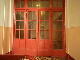 высокие деревянные входные двери со стеклянными вставками в холле первого этажа на лестницу между этажами