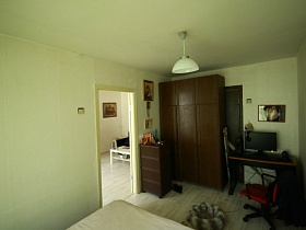 икона над коричневым комодом у входной двери спальной комнаты