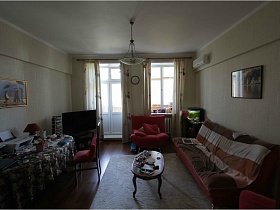 люстра с круглым плафоном на белом потолке гостиной с окном и балконной  дверью в квартире педагога