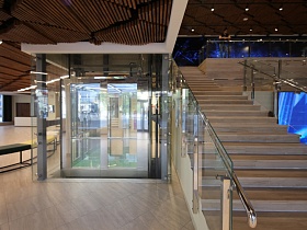 Стеклянный лифтовый холл рядом с лестницей