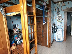 деревянная кровать с лестницей над комодом с настольнной лампой, книжной полкой в детской комнате простой семейной трехкомнатной квартиры