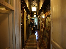 полосатая простая дорожка на полу, шкаф со стеклянными дверцами в узком коридоре художественной деревяной дачи-музей