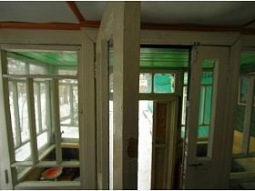 белая краска на окнах и входных дверях веранды зеленой дачи