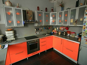 ораньжевые лилии на рифленных стеклянных дверцах навесных шкафчиков ораньжевой кухни семейной трехкомнатной квартиры