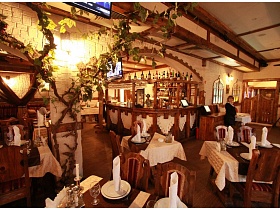 сервированные столики на двоих, четыре и шесть персон в уютном, располагающем к отдыху зале с развлетленной виноградной лозой ресторана с кавказким интерьером
