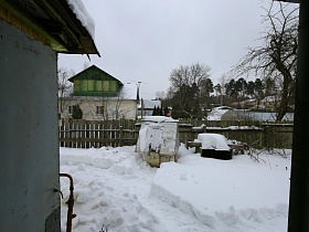 прочищенные дорожки в глубоком снегу к колодцу с крышей и воротам дачного двора
