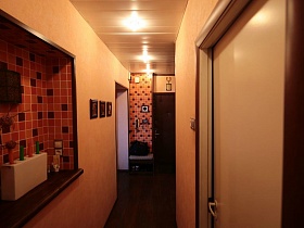 красно-коричнево-бежевая мозаичная отделка встроенной полки и стены у входной двери прихожей квартиры оператора
