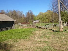 старый разрушенный деревянный штакетный забор вокруг двора с зеленой травой в деревне Троица