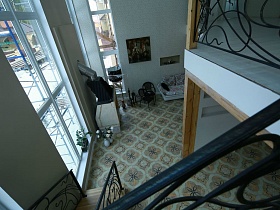окна в два этажа в зоне отдыха с мягким диваном, креслами у камина на полу с бежево-коричневой квадратной плиткой недостроенного элитного дома