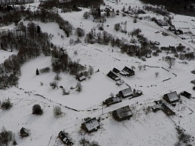 вид сверху на огромные заснеженные просторы с одинокими деревянными домами заброшенной деревни