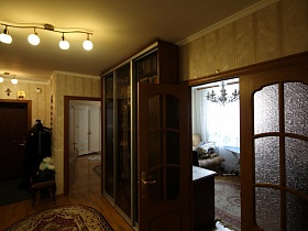 напольная вешалка с одеждой, маленький стульчик на коврике у входной двери в большую современную квартиру врача