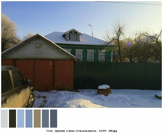 машина напротив коричневых ворот гаража с треугольной крышей, у зеленого высокого забора, вокруг красивого зеленого деревянного дома с белыми наличниками на окнах на селе