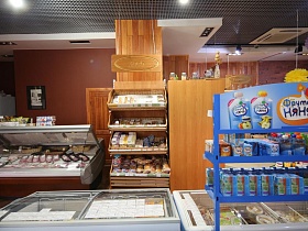 яркая красочная вывеска синего стеллажа с детским питанием у морозильных ларей в центральной части продуктового районного магазина