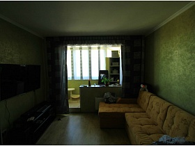 открытая лоджия совмещенная с гостиной за серыми шторами в двухкомнатной квартире новостроя