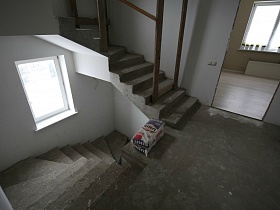 пакеты со строительным материалом на лестничной площадке между лестничными пролетами дома с частичным недостроем