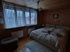 меховой коврик у бежевой кровати с меховым покрывалом и подушками в спальне уютной загородной дачи
