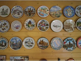 многочисленные и разнообразные декоративные тарелки на деревянной стене гостиной стильного дачного дома