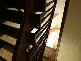 деревянная коричневая лестница с резными перилами в съемном двухэтажном пустом доме в сосновом лесу
