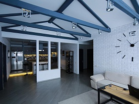 светильники в стиле хай-тек на на деревянных балках в потолке просторной зонированной комнаты стильной скандинавской дачки для съемок кино