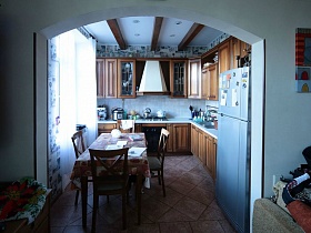 коричневая стенка и серый холодильник в кухне с арочным дверным проемом в семейной трешке