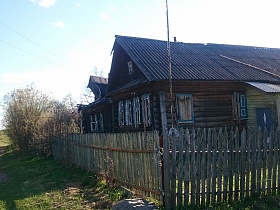 штакетник вокруг деревянного дома из бревен с пристройками на одной из улиц старой деревни 2