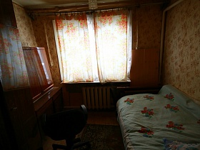 полированный шкаф с антресолью и кресло у стола в спальной комнате на даче