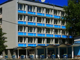 серое пятиэтажное здание гостиницы "Дубна" с голубыми открытыми балконами и уютными столиками на открытой террасе под крышей для съемок кино