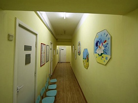 красочные мультяшные картинки на салатневой стене длинного коридора в детском саду