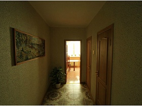 картина на стене и комнатный цветок в углу коридора трехкомнатной квартиры панельного дома