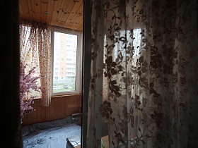 застекленная лоджия,с цветной гардиной на окне, зашитая деревом в трехкомнатной актерской квартире