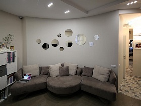 большой дизайнерский диван серого цвета с мягкими подушками в квартире в Строгино