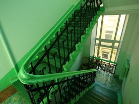 ухоженный подъезд с салатовыми стенами, с зелеными перилами на кованной фигурной решетке, с комнатными цветами на зеленой цветной плитке лестничных площадок жилого многоэтажного дома