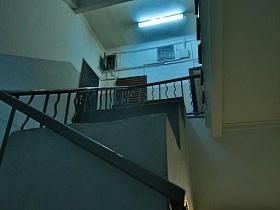 лестничные пролеты с металлическими перилами и бетонными ступенями винтовой лестницы в светлом сером подъезде 12 жилого многоэтажного дома эпохи СССР