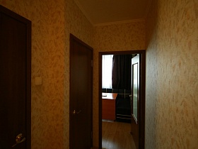 открытая дверь на кухню из длинного коридора современной большой трехкомнатной квартиры в переезде