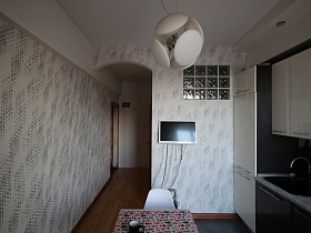 белый плоский телевизор на стене с серыми тесненными обоями, рифленными стеклами окна в ванную комнату современной стильной кухни