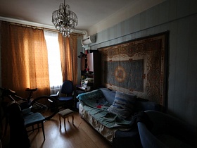 хрустальная ажурная люстра на белом потолке в комнате с голубыми стенами и голубой мягкой мебелью сталинской квартиры
