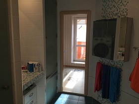 навесной шкаф и полотенца на бежевой стене с мозаичной плиткой, шкаф с ящиками под раковиной в столешнице в ванной комнате современной квартиры