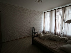 кремовые гардины на высоких окнах спальни с большой кроватью и шкафом для одежды