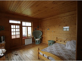 деревянный потолок, стены и пол в спальной комнате с большой деревянной кроватью лвухэтажной дачи музыканта