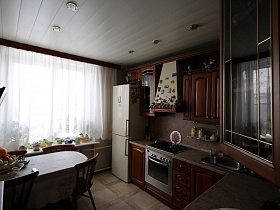 белая короткая гардина на окне кухни с белым подвесным потолком в современной квартире врача