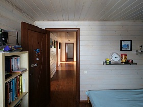просторный холл деревянного трехэтажного дома  из открытой двери спальной комнаты современного добротного дома