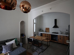общий вид небольшой кухни за разделяющей стеной из гипсокартона с аркой в зонированной комнате современной скандинавской квартиры